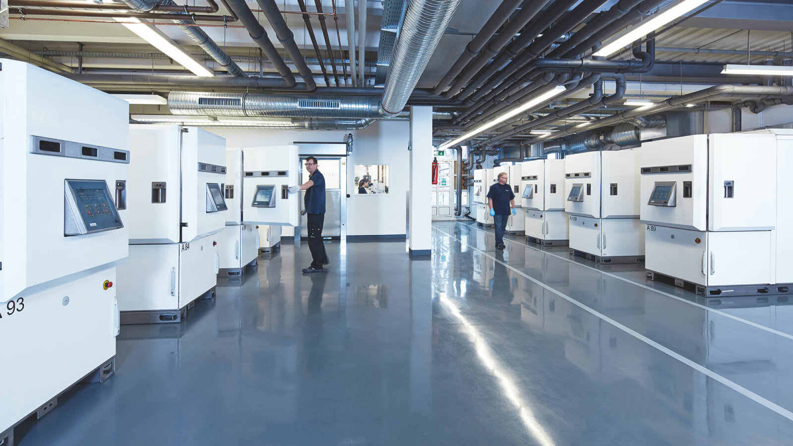 Un hall de production avec des machines de revêtement diamant et des ouvriers travaillant sur les machines.
